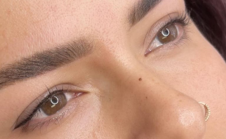 Close-up of a womans face showing well-groomed eyebrows and makeup with defined eyeliner and warm-toned eyeshadow