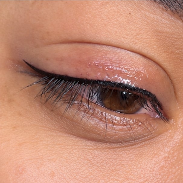 Close-up of an eye with glossy eyeshadow, defined black eyeliner, and dark mascara on lashes